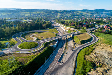 New highway under construction in Poland on national road no 7, E77, called Zakopianka.  Overpass crossroad with traffic circles and viaducts near Rabka. Aerial view in June 2019 - obrazy, fototapety, plakaty