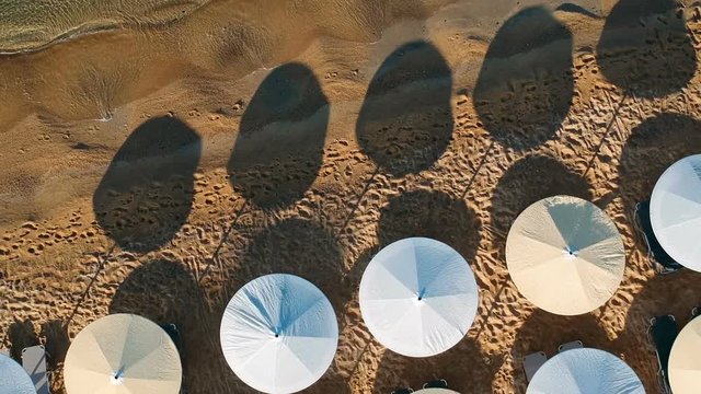 Beach paradise, aerial view of reed umbrella and sunbeds. Beach umbrellas and sunbeds from above