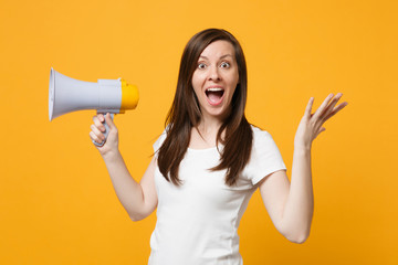Naklejka premium Amazed young woman in white casual clothes keeping mouth open scream in megaphone, spreading hands isolated on bright yellow orange background in studio. People lifestyle concept. Mock up copy space.