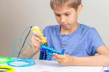Young boy creating with 3d printing pen new object