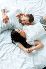 overhead view of happy smiling couple lying together in bed