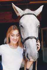 Fototapeta premium Cute girl with a horse. Lady in a white t-shirt. Woman in a summer park