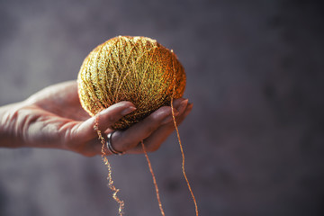 Gold skein yarn on wooden background. Female hobby and knitting.