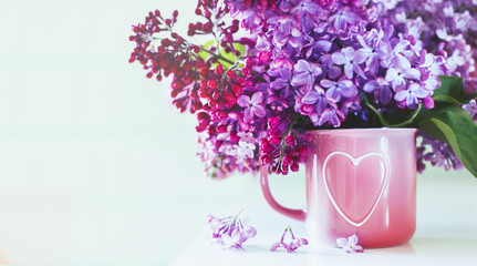 It's spring. Fresh fragrant bouquet of lilac in a vase with a heart on a mint wooden background. Romance