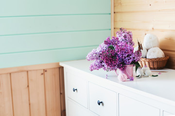 Crochet and knitting. Women's working space. Bouquet of lilac, yarn, crochet hooks on the white dresser in the mint wooden room. Favorite hobby.