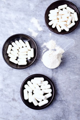 Scoop of Whey Protein, Hydrolyzed Collagen Type I, L-Proline and L-Lysine capsules. Supplements to support collagen production. Bright stone background. Top view. Copy space. 