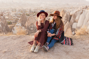 Traveling women wearing authentic boho chic style poncho, sweeter and hats smiling and have a fun  in Cappadocia valley, Turkey. Travel and wanderlust concept. Copy space background. © prystai