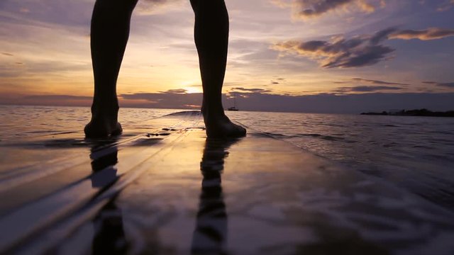 SUP paddle board on the beach, close up of standing legs and paddle