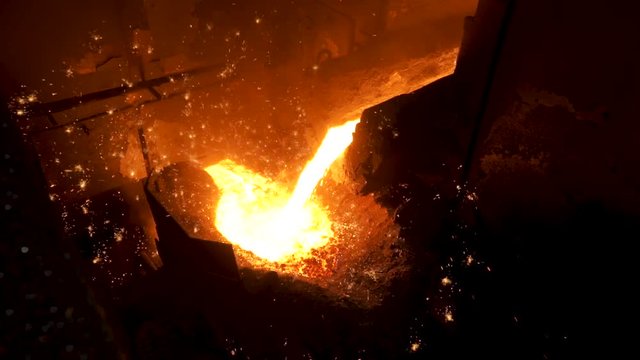 Sparks on black background from the process of pouring hot steel, heavy industry. Stock footage. Close up for iquid metal flowing from blast furnace.