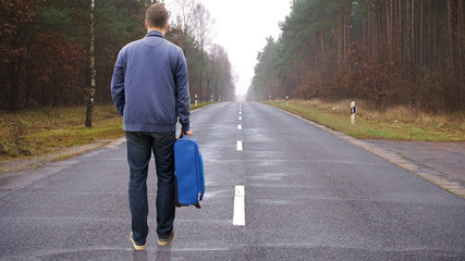 junger Mann trägt seinen Koffer auf einer Straße