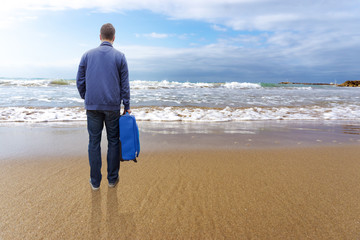 lonely man travelling with his bag to the beach