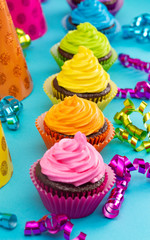 Rainbow Colored Frosted Chocolate Cupcakes on Teal Background