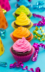 Rainbow Colored Frosted Chocolate Cupcakes on Teal Background