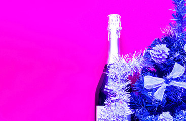 Brilliant Christmas decor.Bottle champagne decorated in festive theme on plastic pink background.