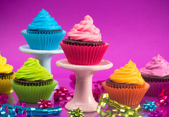 Rainbow Colored Frosted Chocolate Cupcakes with Confetti and Bows for a Party