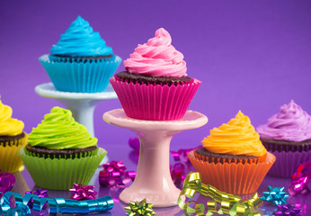 Rainbow Colored Frosted Chocolate Cupcakes with Confetti and Bows for a Party