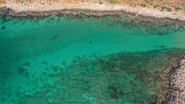 Aerial drone top view photo of turquoise organised beach forming a small heart shaped lagoon and mountainous seascape of Stavros, Chania, Crete island, Greece