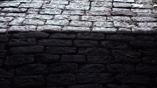sombra avanza sobre un piso de adoquines 