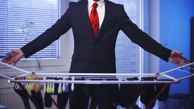 Businessman doing laundry housework 4K. Medium shot of headless male businessman in focus while hanging socks after washing. Windows in background