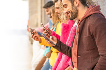 Group of multiracial people standing watching  with their cell phones. Young people always connected to the internet and social network concept. Image fades to pure white to leave room for text.