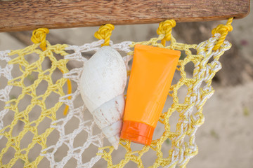 Jar of sunscreen and shell on the hammock. Skin protection concept.