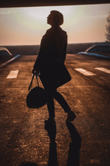 silhouette of a woman with travelbag on the road
