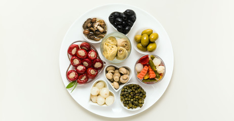 banner of Italian traditional pickles on a plate. tuna stuffed peppers, artichokes in oil, olives, mushrooms, capers. copy space.
