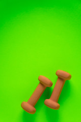 Fitness equipment with womens yellow orange weights/ dumbbells isolated on a lime green with copyspace background with copyspace
