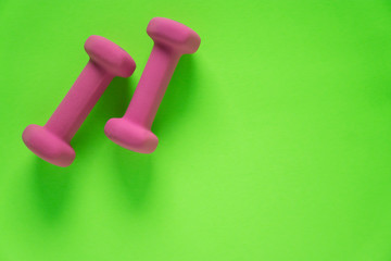Fitness equipment with womens pink weights/ dumbbells isolated on a lime green background with copyspace