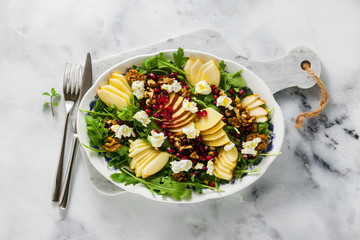 Fototapeta na wymiar Pomegranate & Pear Green Salad with Ginger Dressing on white marble . healthy breakfast or lunch