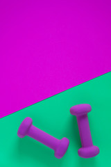 Fitness equipment with womens purple weights/ dumbbells isolated on a teal green background with copyspace
