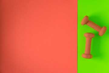 Fitness equipment with womens yellow orange weights/ dumbbells isolated on a lime green and orange with copyspace background with copyspace