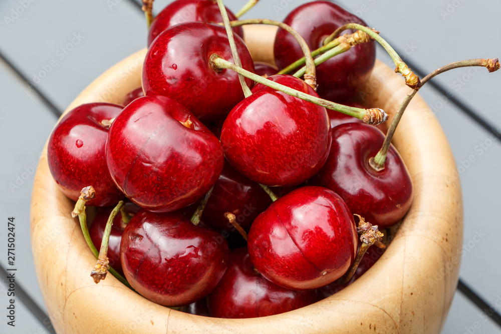 Wall mural cherries in a wooden bowl on a garden table