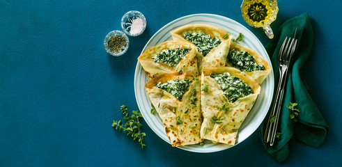 Traditional Italian pancakes crepes with spinach and ricotta on a served blue table. healthy vegetarian diet