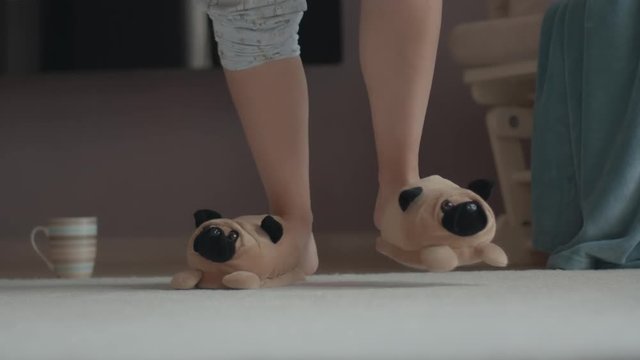 Happy girl dancing wearing doggy bedroom slipper and pajamas at home. Funny dance. Happy emotions. Close up shot