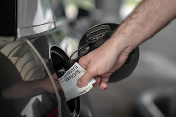 Tanken und Autofahren wird teuerer, Mann mit Geldscheinen an der Zapfsäule an der Tankstelle