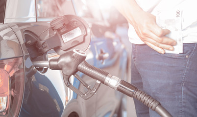 Tanken und Autofahren wird teuerer, Mann mit Geldscheinen an der Zapfsäule an der Tankstelle