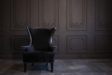 Stylish black chair against a dark gray wall - obrazy, fototapety, plakaty