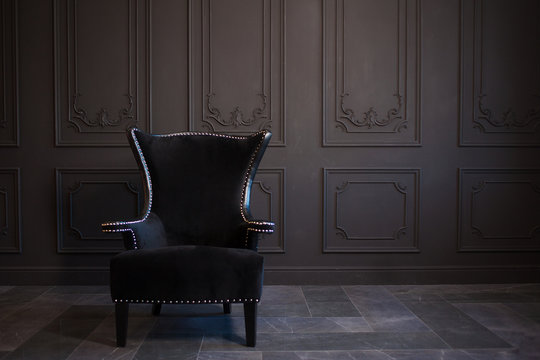 Stylish black chair against a dark gray wall