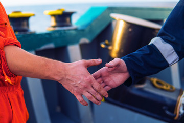 marine contractor businessman handshaking with worker on the ship. Handshake of two boilersuits with different color. Business shipping background