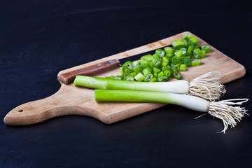 Fresh green organic chopped onions and knife on a cutting board.