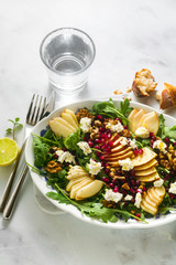 Pomegranate & Pear Green Salad with Ginger Dressing on white marble . healthy breakfast or lunch