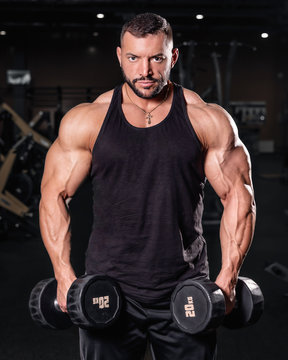  Bodybuilder in the gym. Sports photo shoot. Man's fitness. Training and exercises with dumbbells. Men's photo shoot in low key. Athletic build. young man lifting weights in gym