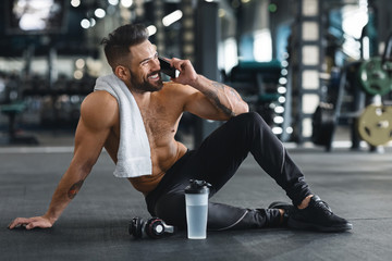 Muscular guy talking on cellphone after training at gym