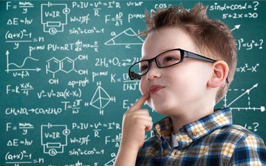 Cute little schoolgirl in glasses on blackboard background