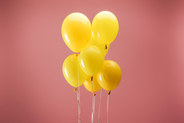 yellow festive balloons on pink background, party decoration © LIGHTFIELD STUDIOS