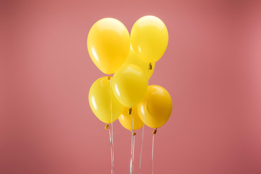 Fototapeta yellow festive balloons on pink background, party decoration