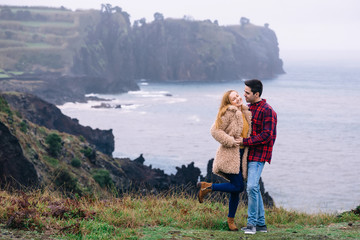 nature. ocean and rocks. guy and girl hug and smile.