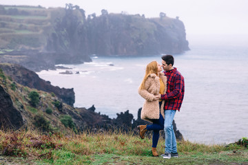 The guy and the girl are closed eyes and want to kiss. rocks on