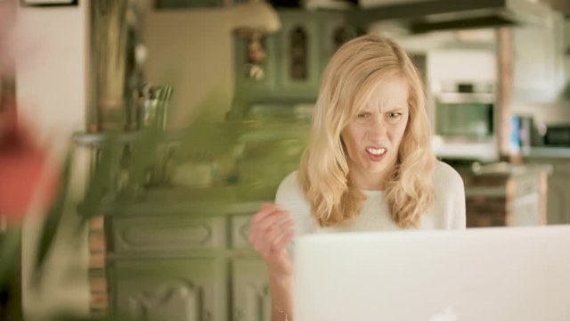Woman making a weird disgusted face using her laptop at home